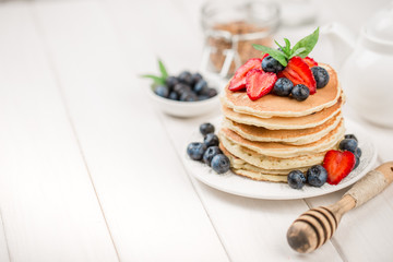 Classic american pancakes with fresh berry on white wood background. Summer homemade breakfast.