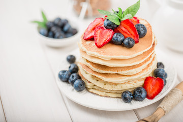 Classic american pancakes with fresh berry on white wood background. Summer homemade breakfast.