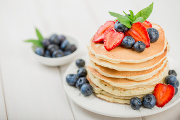Classic american pancakes with fresh berry on white wood background. Summer homemade breakfast.