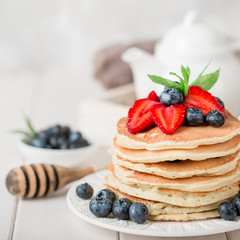 Classic american pancakes with fresh berry on white wood background. Summer homemade breakfast.