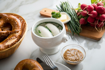 Münchener Weißwurst in Terrine mit bayrischer süßen Senf, Brezel, Radieschen, Schnittlauch und Butter auf Marmor Tisch