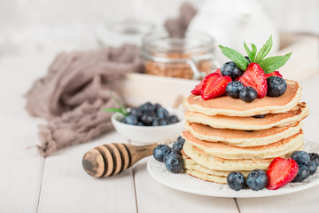 Classic american pancakes with fresh berry on white wood background. Summer homemade breakfast.