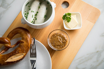 Münchener Weißwurst in Terrine mit bayrischer süßen Senf, Brezel und Butter auf Holz Brett