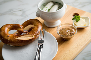 Münchener Weißwurst in Terrine mit bayrischer süßen Senf, Brezel und Butter auf Holz Brett