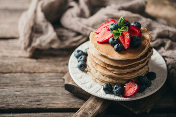 American pancakes with fresh berry on wood background. Summer homemade breakfast.