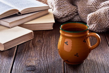 Still life with old wooden table, mug of tea and books.