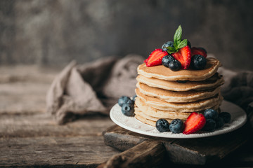 American pancakes with fresh berry on wood background. Summer homemade breakfast.
