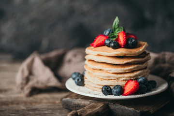 American pancakes with fresh berry on wood background. Summer homemade breakfast.