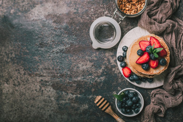 American pancakes with fresh berry and granola on metal background. Summer homemade breakfast.