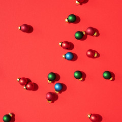 Christmas colored baubles. Festive pattern made of new year baubles on red background. Flat lay, top view. Minimal design greeting card