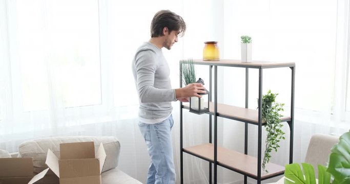 Man having fun while unpacking boxes and decorating his new house