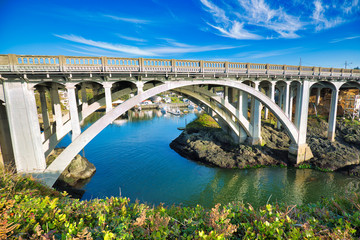 Fototapeta na wymiar U.S. 101 highway over the entrance to Depoe Bay, Oregon, touted as the world's smallest natural navigable harbor. Its narrow, 50 foot wide channel (below bridge) leads directly to the Pacific Ocean.