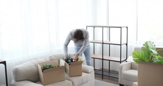 Man moving into new house arranging plants and lantern on shelf
