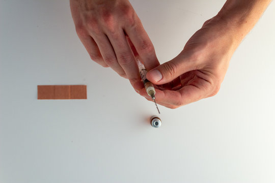 Preparing A Shot With A Vial And Bandage Against White Background.