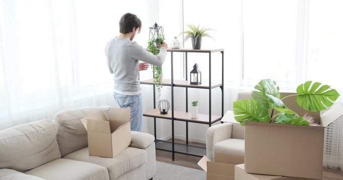 Young man unpacking box and decorating his new house