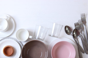 Set of dishes and kitchen utensils on a light background top view.