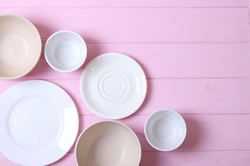 Set of dishes and kitchen utensils on a colored background top view.
