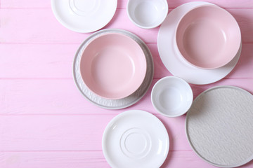 Set of dishes and kitchen utensils on a colored background top view.