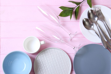 Set of dishes and kitchen utensils on a colored background top view.