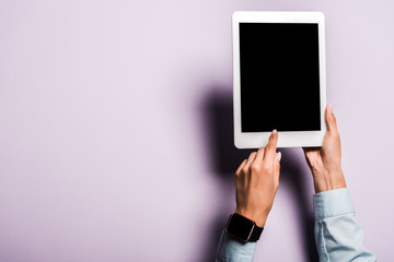 cropped view of woman pointing with finger at digital tablet with blank screen on purple