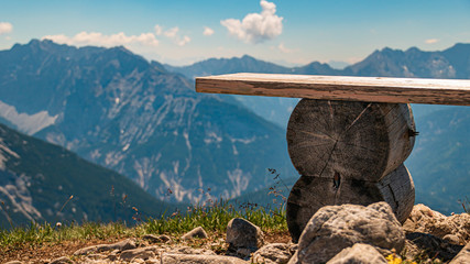 Fototapeta premium Beautiful alpine view with a wooden bench at the famous Karwendel summit near Mittenwald, Bavaria, Germany