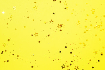 Golden star sparkles on yellow background. Christmas and New year concept. Festive backdrop with copy space