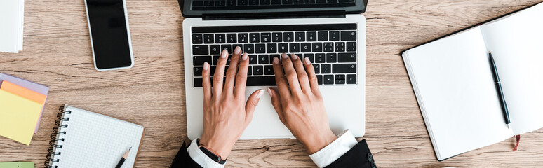 Fototapeta na wymiar panoramic shot of woman typing on laptop keyboard in office