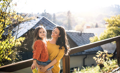 A portrait of young mother with a small daughter in park in autumn.