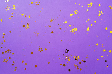 Golden star sparkles on violet background. Christmas and New year concept. Festive backdrop with copy space