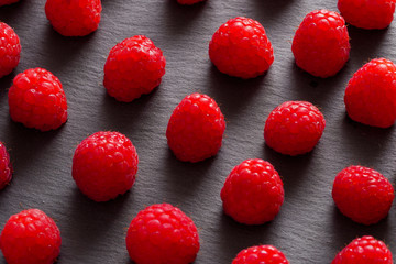 Closeup view of some raspberries over a blackboard plate.