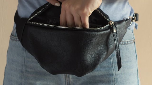 Female hand put a passport in a bag. Tourist woman take documents to travel in hip pack belt bag