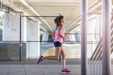 Naklejka premium Young woman running in a urban city area