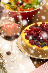 christmas dinner and eating concept - close up of berry cake and other food on table at home over snow