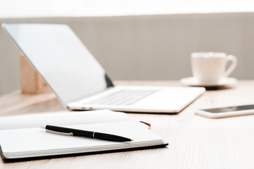selective focus of notebook and pen near gadgets on table
