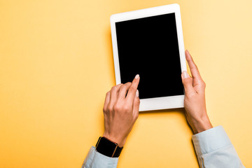 cropped view of girl pointing with finger at digital tablet with blank screen on orange