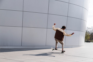 Afro skateboarder outdoors doing trick on white