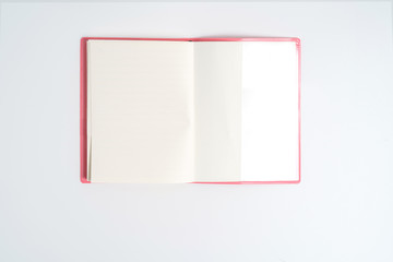 Pink notebook on white desk. Business minimal concept for women. Flat lay, top view, copy space