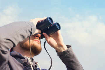 Man with the field-glass watches birds. Ornithology. Birdwatching