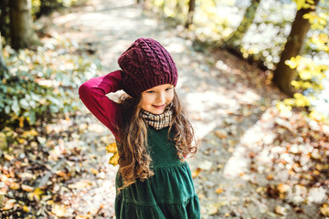 High angle view of a small toddler girl standing in forest in autumn nature.