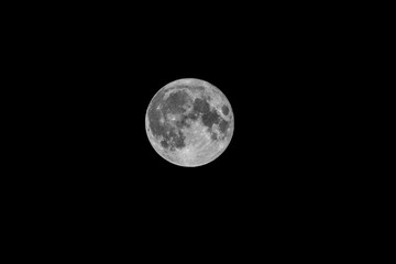 A portrait of a full moon shining bright at night in the darkness of endless space.