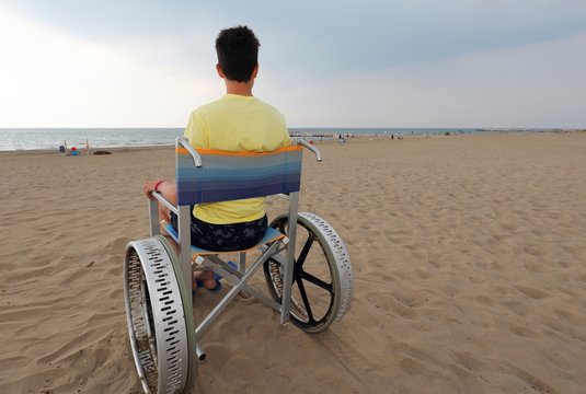 wheelchair with young boy on the beach in summer
