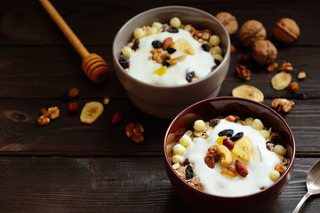 Muesli with milk, nuts, dried fruits on wooden brown background