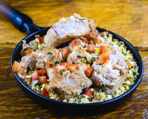 Typical pork ribs from Brazil. Roast pork with farora, minced vegetables and gravy. served on the plate. Food from the state of minas gerais.