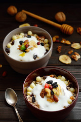 Granola with yougurt, nuts, dried fruits on wooden brown background
