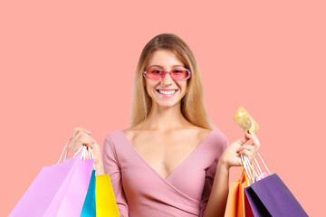 Black friday season sale concept. Attractive young woman with long blonde hair, wearing sexy pink dress, holding many different blank shopping bags. Bright isolated background, copy space, close up.