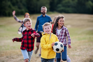 Group of school children with teacher on field trip in nature, playing with a ball.