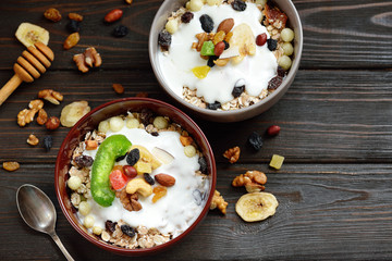 Muesli with milk, nuts, dried fruits on wooden brown background