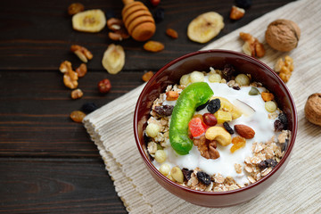 Muesli with milk, nuts, dried fruits on wooden brown background