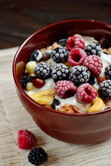Muesli with milk, nuts, fresh berries on wooden brown background