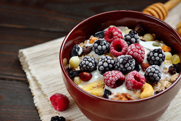 Granola with yougurt, nuts, fresh berries on wooden brown background